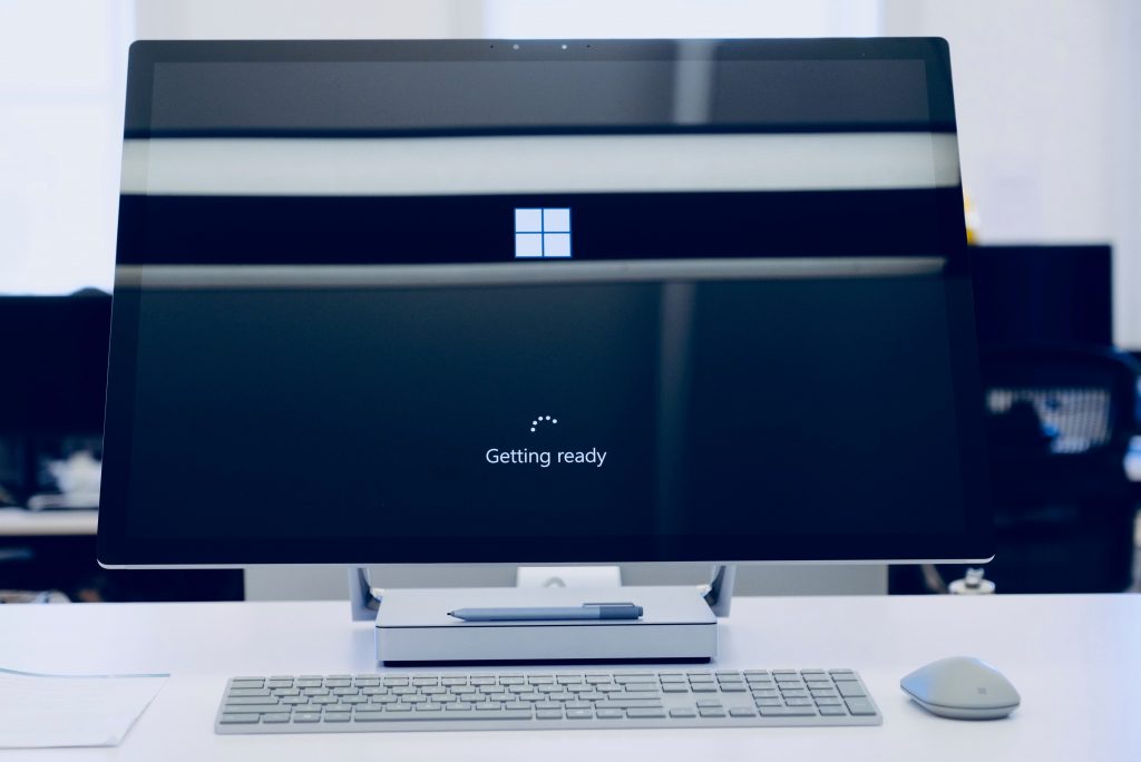Desktop computer showing a Windows getting ready screen with keyboard and mouse on a clean office desk.