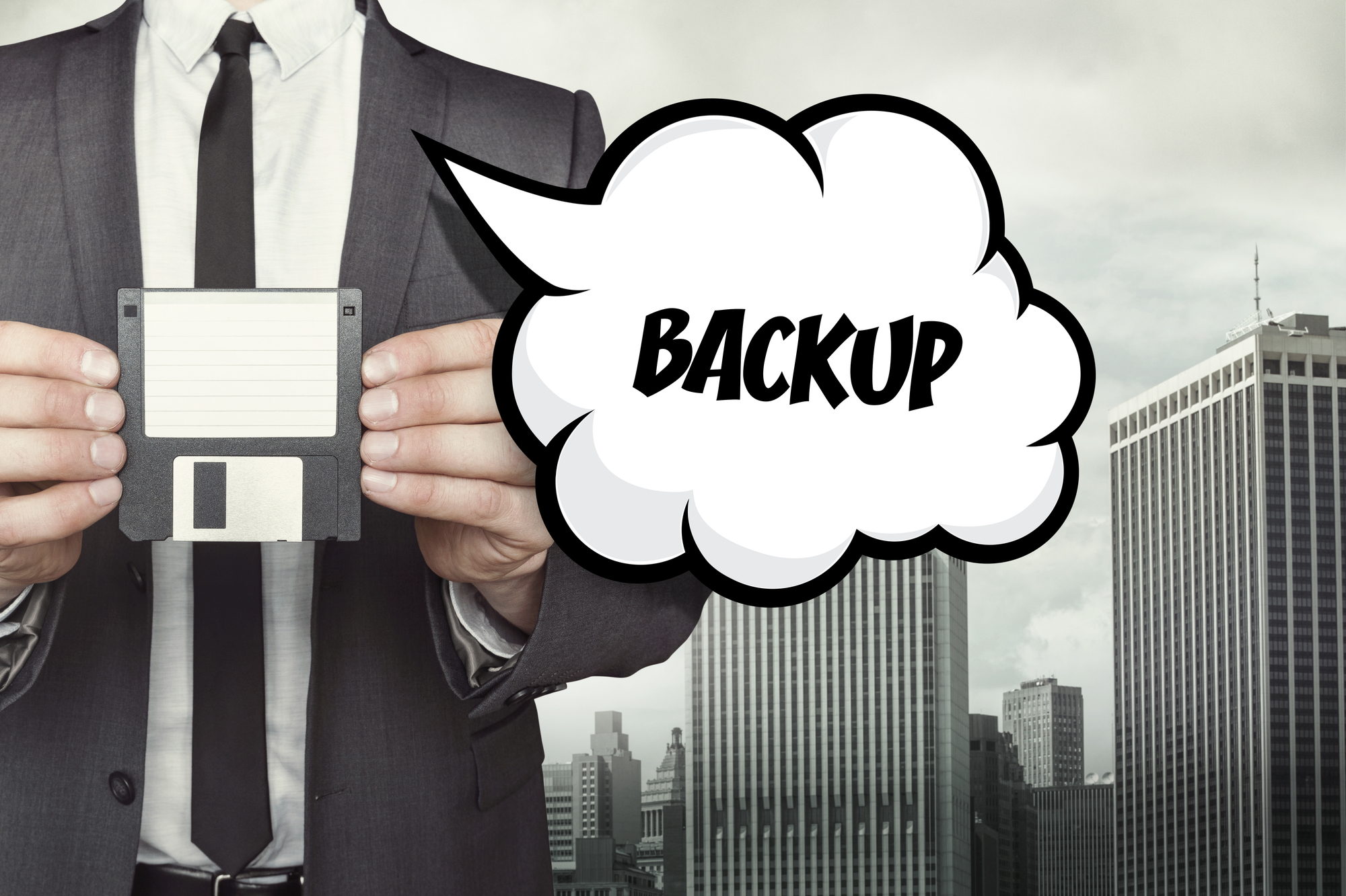 Business professional holding a floppy disk with backup text, representing data backup and recovery.