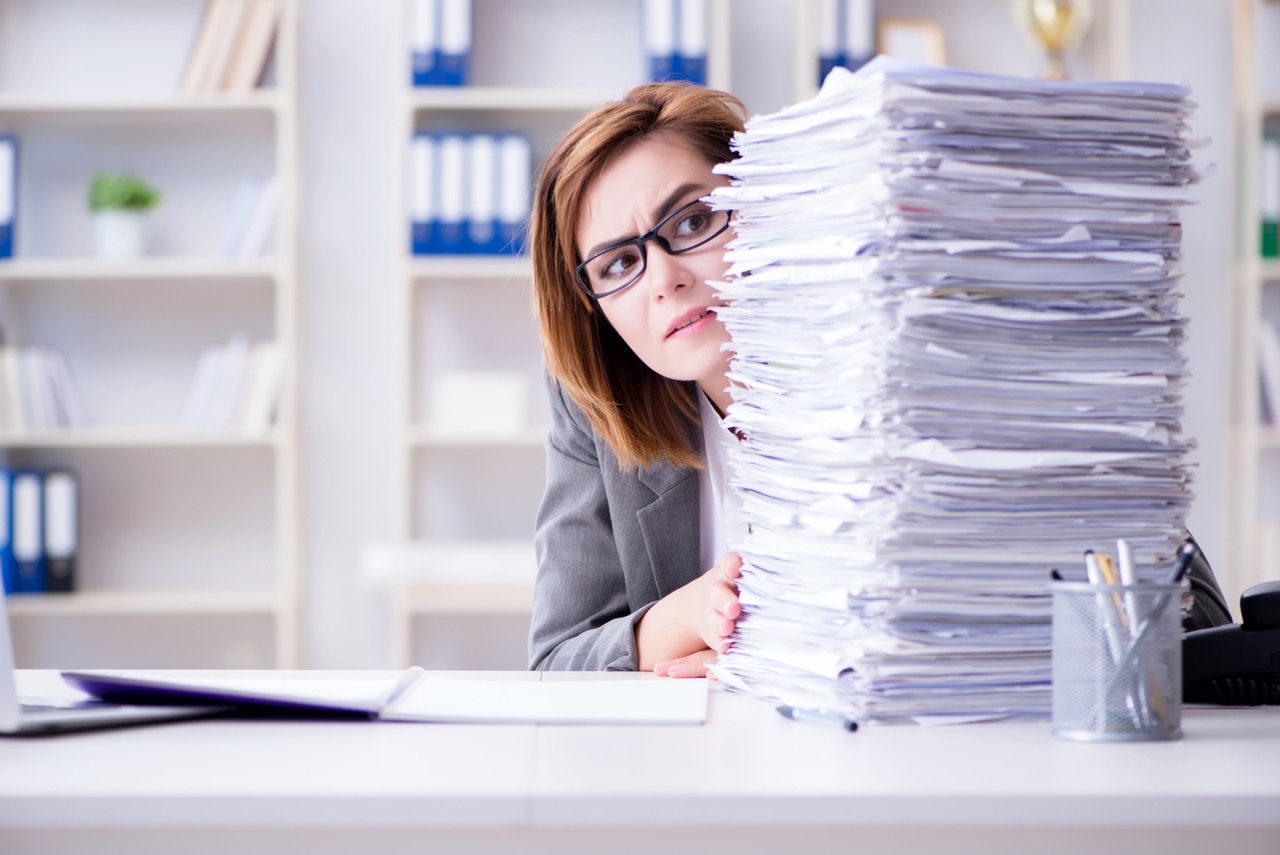 Accountant looking over a large stack of paperwork, representing an IT checklist for accounting firms.